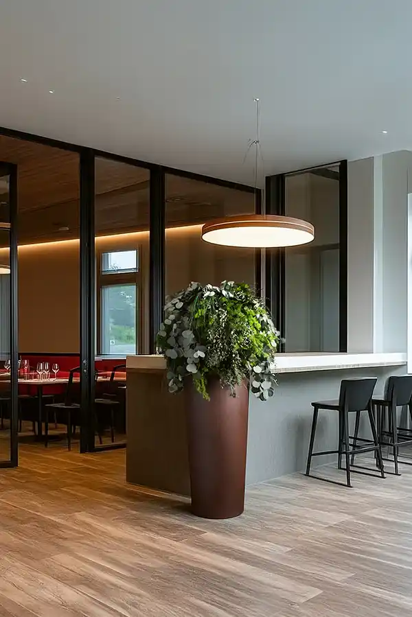 Hohe Vase mit modernem Moosball aus Moos und Pflanzen, dekoratives Highlight im Restaurantbereich.