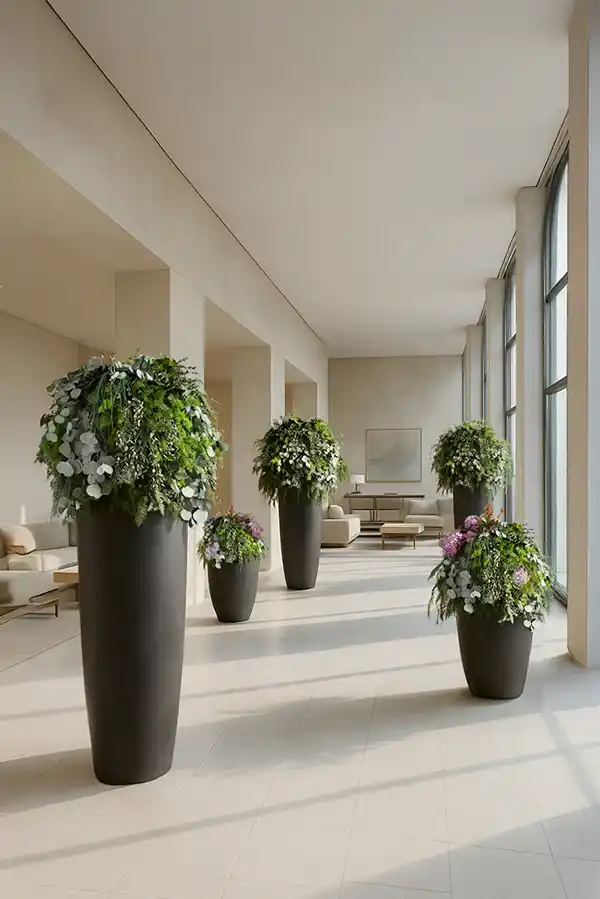 Große schwarze Vasen mit Moosbälle aus Moos und Pflanzenarrangements von MoosMoos, dekorativ in einer hellen Lobby.
