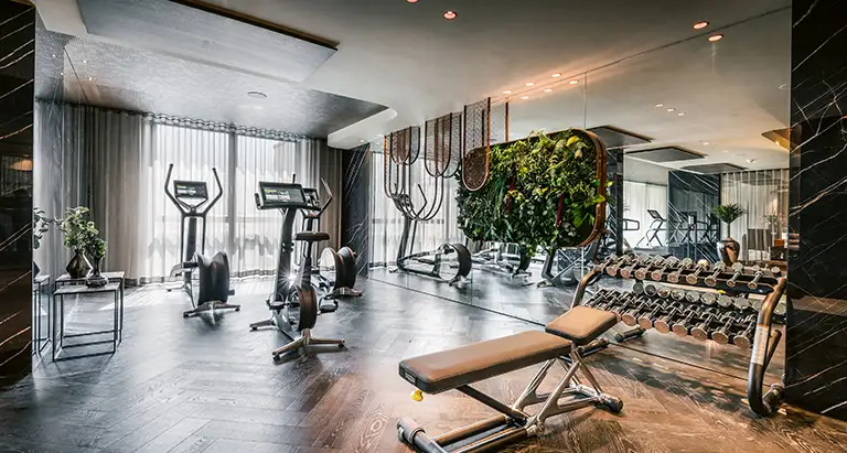Trainingsraum mit modernen Fitnessgeräten und einer lebendigen Wand aus Moos, die das Studio-Design von MoosMoos nachhaltig aufwertet.