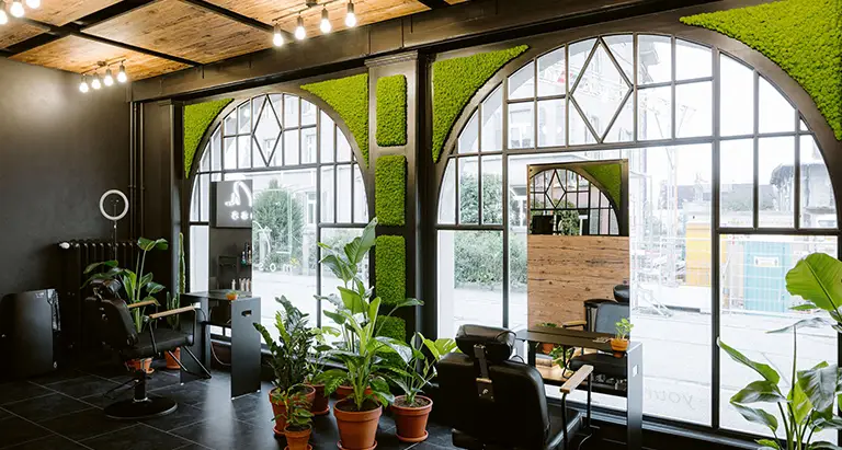 Friseursalon mit großen Fenstern, schwarzen Wänden und dekorativen Wänden aus Moos von MoosMoos, stilvolles Naturambiente im Interior Design