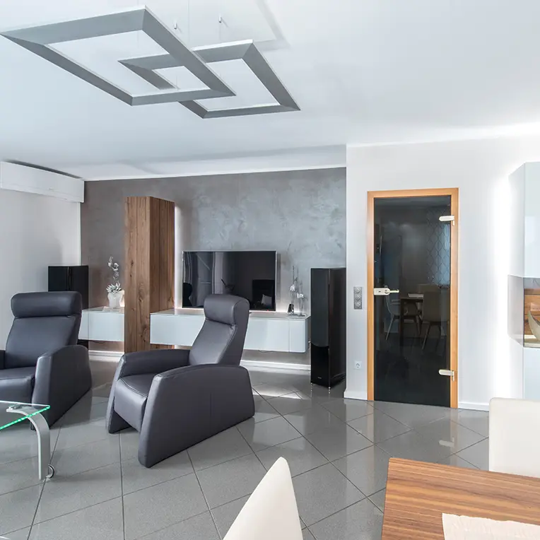 Elegantes Wohnzimmer mit grauer Betonoptik-Wand und Designer-Deckenleuchte, Premium Innenraumgestaltung Uwe Walter MOOSMOOS Verbund Mallorca