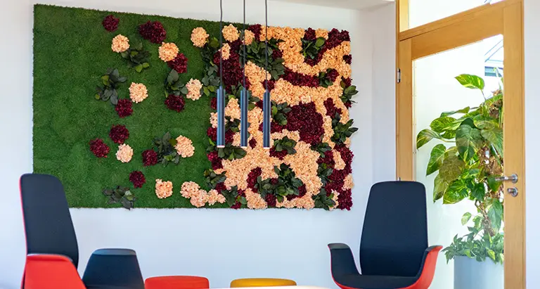 Große florale Mooswand mit roten und apricotfarbenen Blüten in modernem Besprechungsraum
